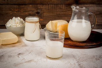 Selection of organic farming household dairy products - milk, cream (yogurt), cheese, cottage cheese, white stone concrete table. 