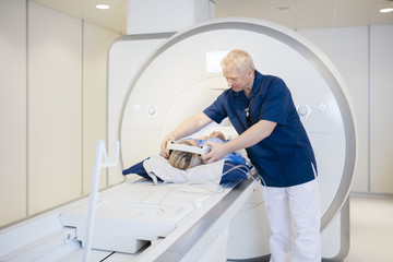 Radiologist Putting Headphones On Patient Undergoing MRI Scan