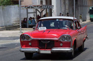 Fototapeta na wymiar Amerikanischer roter Oldtimer mit weißem Dach fährt auf der Hauptstrasse in Havanna Kuba - Serie Kuba Reportage