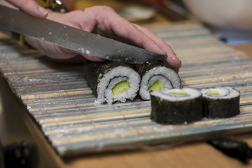 Maki sushi with cucumber being cut