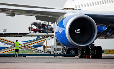 Loading luggage in the airplane. Passenger commercial air transportation. Baggage service traffic in the airport. Shipping tape for loading baggage.