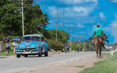 Blauer amerikanischer Oldtimer mit eine Reiter auf der Landstraße nach Santa Clara - Serie Kuba Reportage
