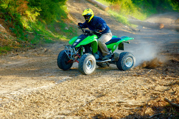 racer with yellow helmet on green quad enjoying his ride outdoors. © jozefklopacka