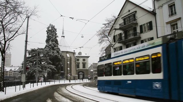 Blue Tram in the city center of Zurich, Switzerland in winter with snowy roads and cloudy sky