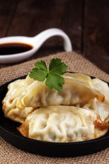 A plate of Japanese gyoza dumplings sitting on a rustic wooden t
