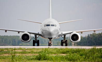 Front view of white plane before takeoff on the runway. Passenger airliner takes off. Passenger commercial air transportation. Mid-range aircraft. Spotting in the airport. - obrazy, fototapety, plakaty
