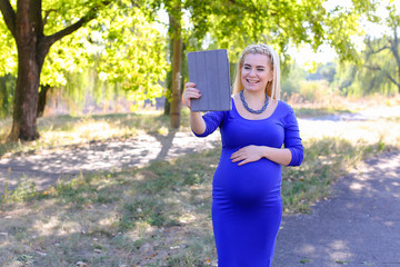 Good-Looking Pregnant Girl Holds Tablet And Talks on Skype, Welc