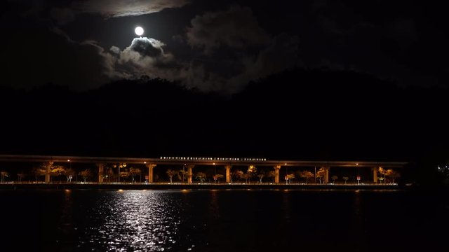 4K An elevated train travels in the bridt over a lake during the nigth with the moon in the Park Dahu at Taipei asian city, cityscape of Taiwan-Dan