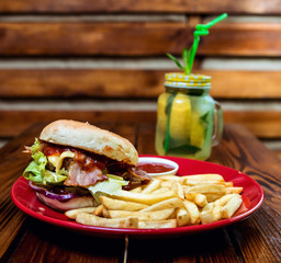 Big cheeseburger and chips on a plate.