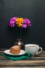 flowers in a vase, a cup with a drink and a cupcake