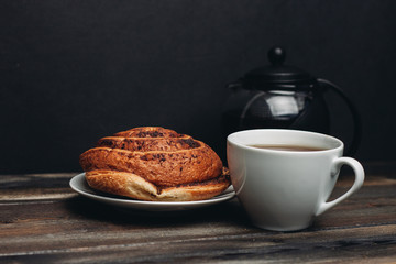 bun with cinnamon and a white cup of tea