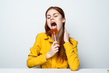a woman licks a lollipop, a yellow shirt
