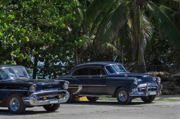 Zwei schwarze Oldtimer parken am Strand von Varadero Kuba - Serie Kuba Reportage