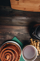 wooden background and bun with cinnamon, cup with a drink