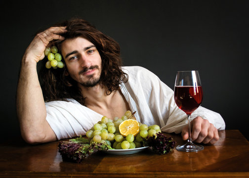 half naked curly guy at the table with a plate of grapes and a glass of wine photo