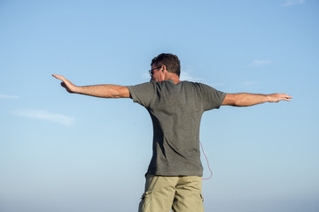 Man viewed from back stretches arms