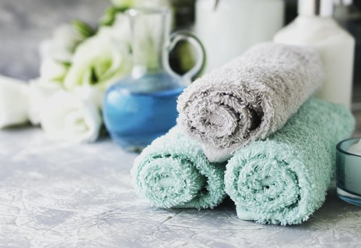 Spa set on a white marble table with a stack of towels, selective focus