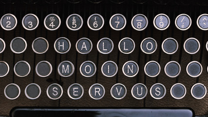 Hallo, Moin und Servus, Worte in Tastatur auf alter Schreibmaschine