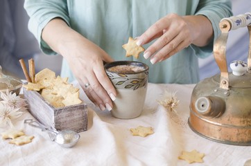 woman's hands holding a cup of cocoa over the dinner table, selective focus