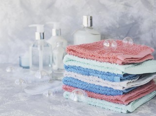 stack of towels for bathroom bottles on a white marble background, space for text, selective focus