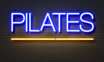 Obraz premium Pilates neon sign on brick wall background.