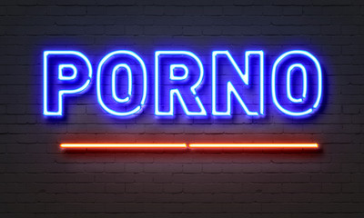 Porno neon sign on brick wall background.