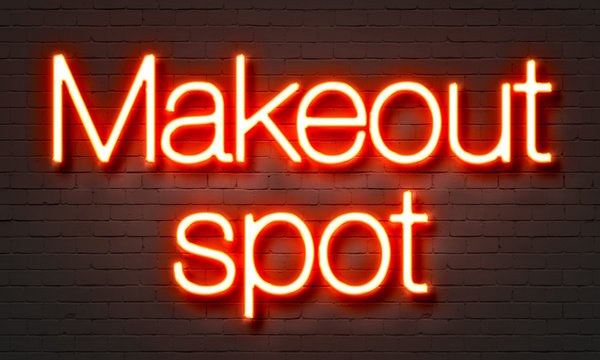 Makeout spot neon sign on brick wall background.