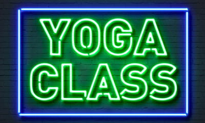 Yoga class neon sign on brick wall background.