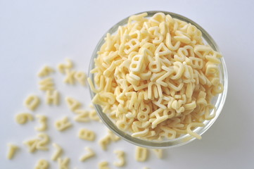 Alphabet pasta for children's meals. ABC pasta. Dry pasta in a glass bowl isolated on white
