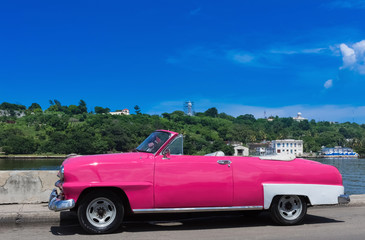 Fototapeta na wymiar Pinker amerikanischer Cabriolet Oldtimer parkt auf dem Malecon in Havanna Kuba - Serie Kuba Reportage