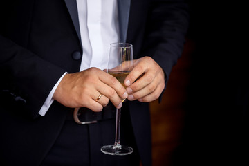 Groom holding glass with champagne. Wedding party