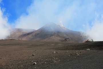 Smoking Etna volcano in Sicily, Italy. Cars with hiking expedition in the foothills of Mount Etna 