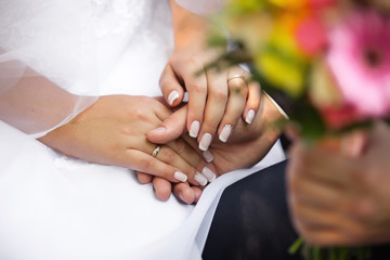 Groom holding bride's hands with wedding ring