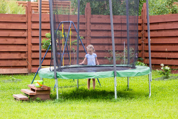 little girl washes her trampoline in backyard