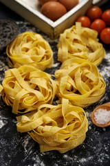 Fettuccine pasta italian food still life rustic over black wood background.
