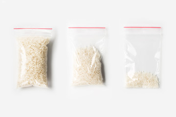 Set of three EMPTY, HALF AND FULL Plastic transparent zipper bag with Uncooked white basmati rice isolated on white. Vacuum package mockup with red clip. Concept © pavelvinnik