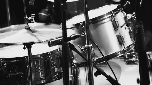Drummer plays large drum set at concert; close up; black and white shot; unrecognizable person;