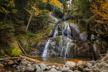 Waterfall in autumn with yellow leaves and silky water