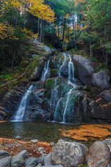 Obraz premium Waterfall in autumn with yellow leaves and silky water