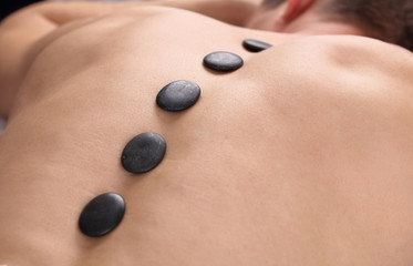 Man having massage with volcanic rocks. Relaxation, body care treatment, spa, wellness concept.