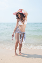 Pretty Asian woman posing relax on the beach with pink hat.