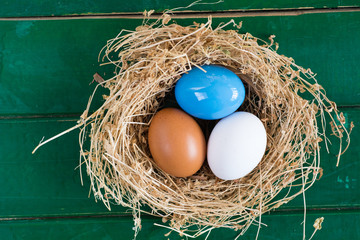 Easter eggs in nest on rustic wooden background, selective focus image, Card Happy Easter - space for text 