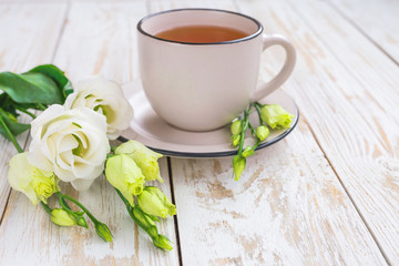 Fototapeta na wymiar Cup of hot tea and white eustoma flowers