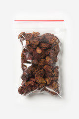 Plastic transparent zipper bag with home dry strawberries isolated on white, Vacuum package mockup with red clip. Concept.