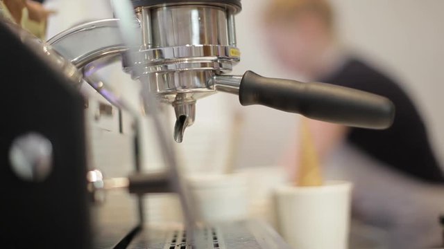 Barista making fresh coffee going out from a coffee espresso machine into a glas. Macro shot in Full HD