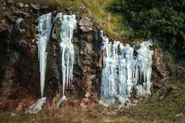 Fototapeta na wymiar Frozen waterfall in winter time in the mountains