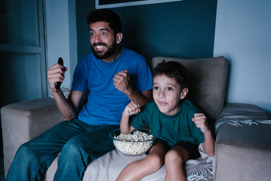 Father and son watching TV and cheering at night