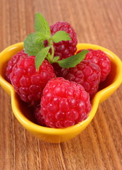 Fresh raspberries and lemon balm on wooden surface, healthy food