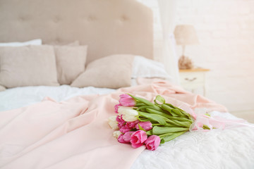 Nice bouquet with pink and white tulips  on bed