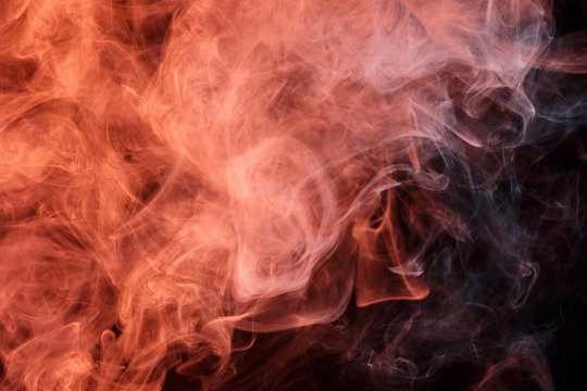 Abstract smoke Weipa. Personal vaporizers fragrant steam. The concept of alternative non-nicotine smoking. Orange smoke on a black background. E-cigarette. Evaporator. Taking Close-up. Vaping.